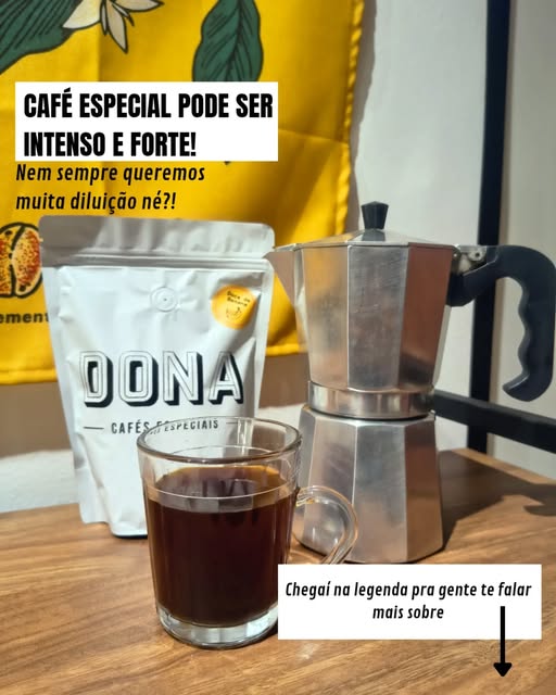Pacote de café com o logotipo DONA ao lado de uma cafeteira Moka e um copo de café, sobre pano amarelo